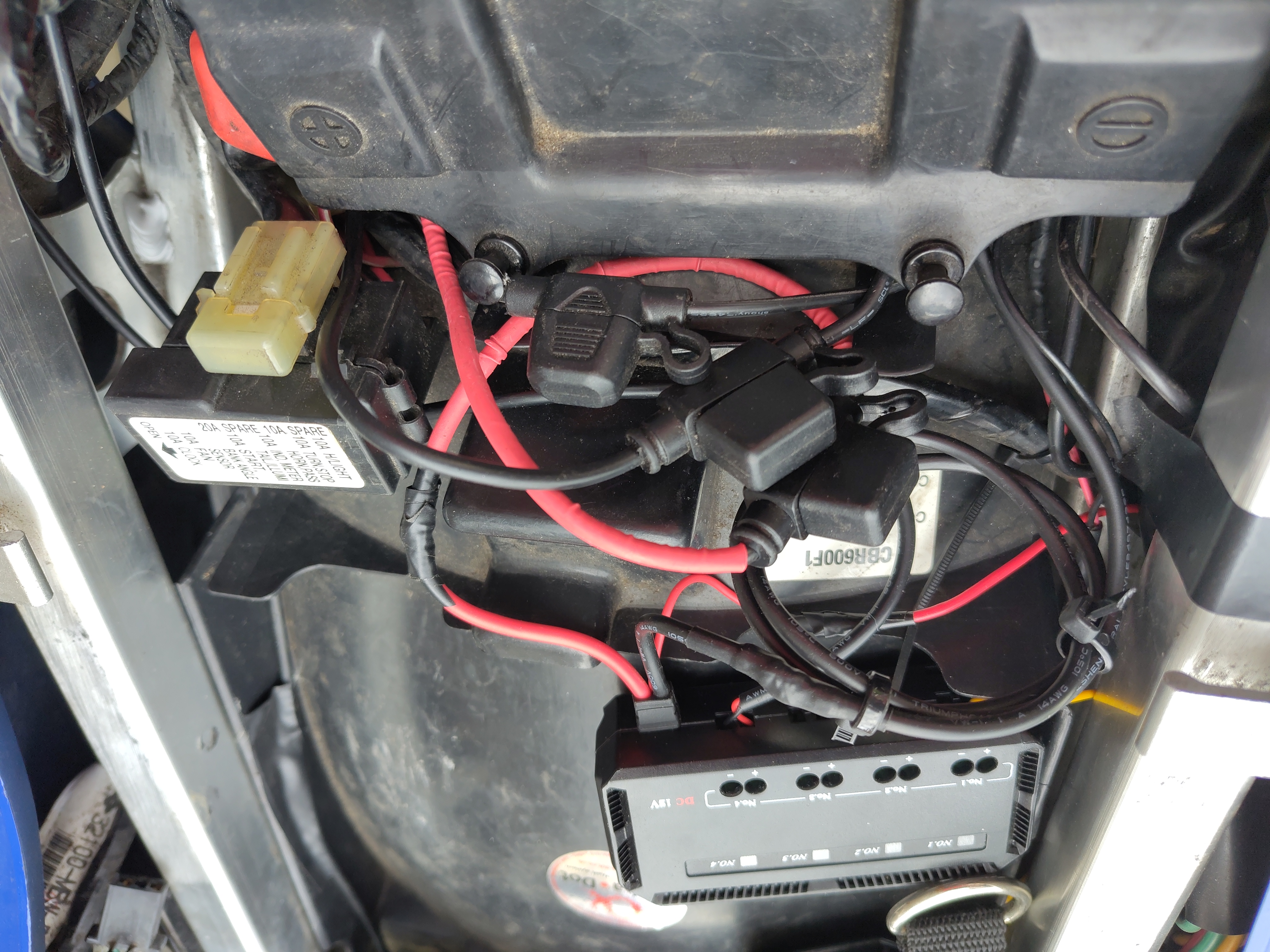 Under the seat of my bike, a small black accessory fuse box with 4 LEDs and a mess of red and black cables